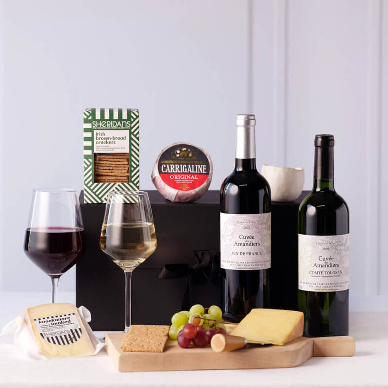 Wine and Cheese Gift Set featuring red and white wine bottles, artisan Irish cheeses, crackers, and grapes arranged with festive holiday decorations &ndash; available at GiftsDirect.com