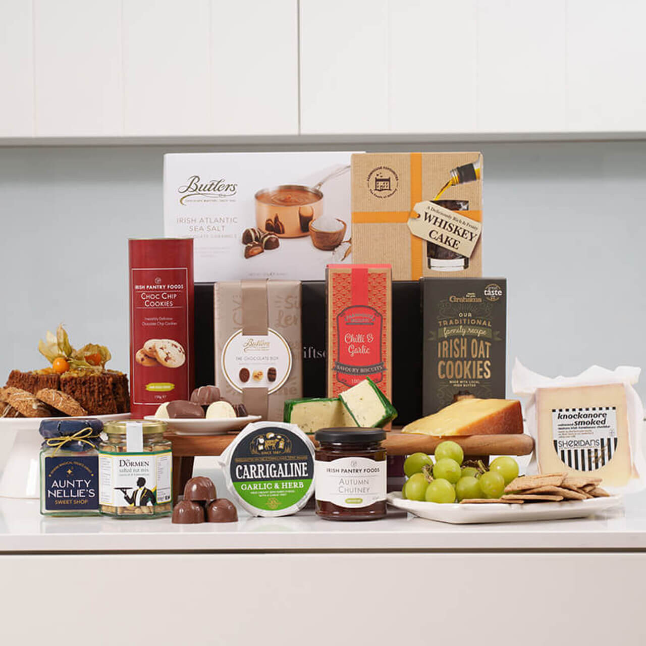 Savoury and Sweet Irish Gift Box featuring Carrigaline cheese with grapes, whiskey cake, chocolate and ginger cookies, Butlers chocolates, gourmet nuts, crackers, chutney, and festive treats beautifully arranged &ndash; available at GiftsDirect.com